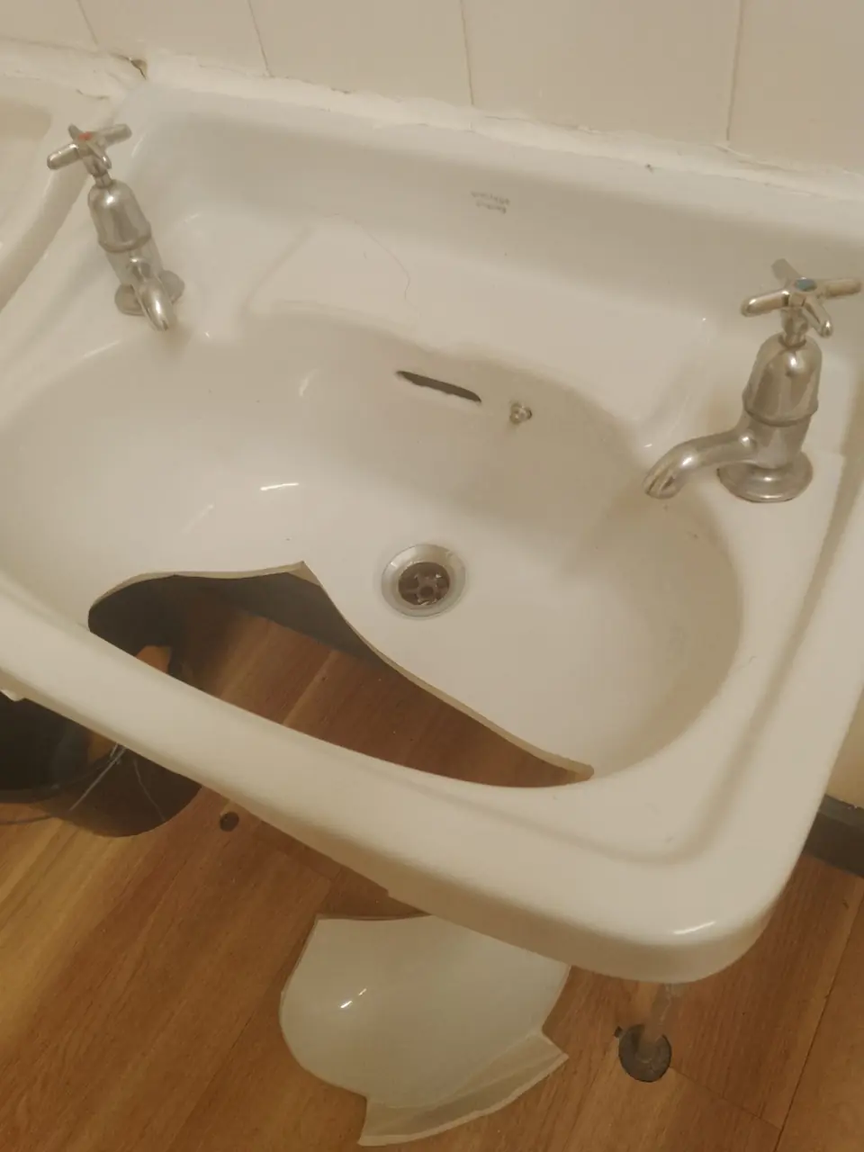 Cracked ceramic basin with chrome pillar taps awaiting an emergency repair