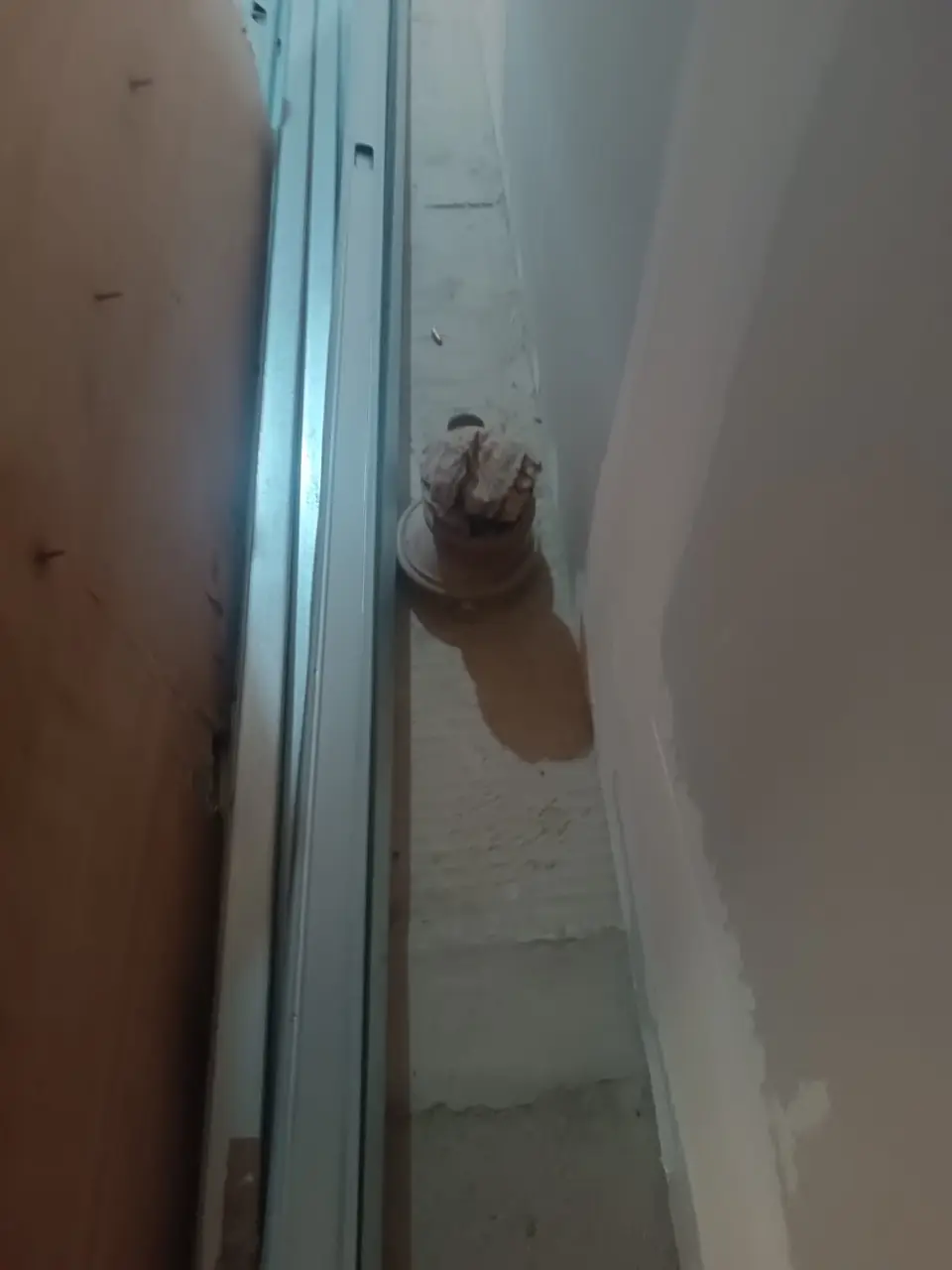 Water mark on a concrete floor beside a waste outlet next to a partition wall