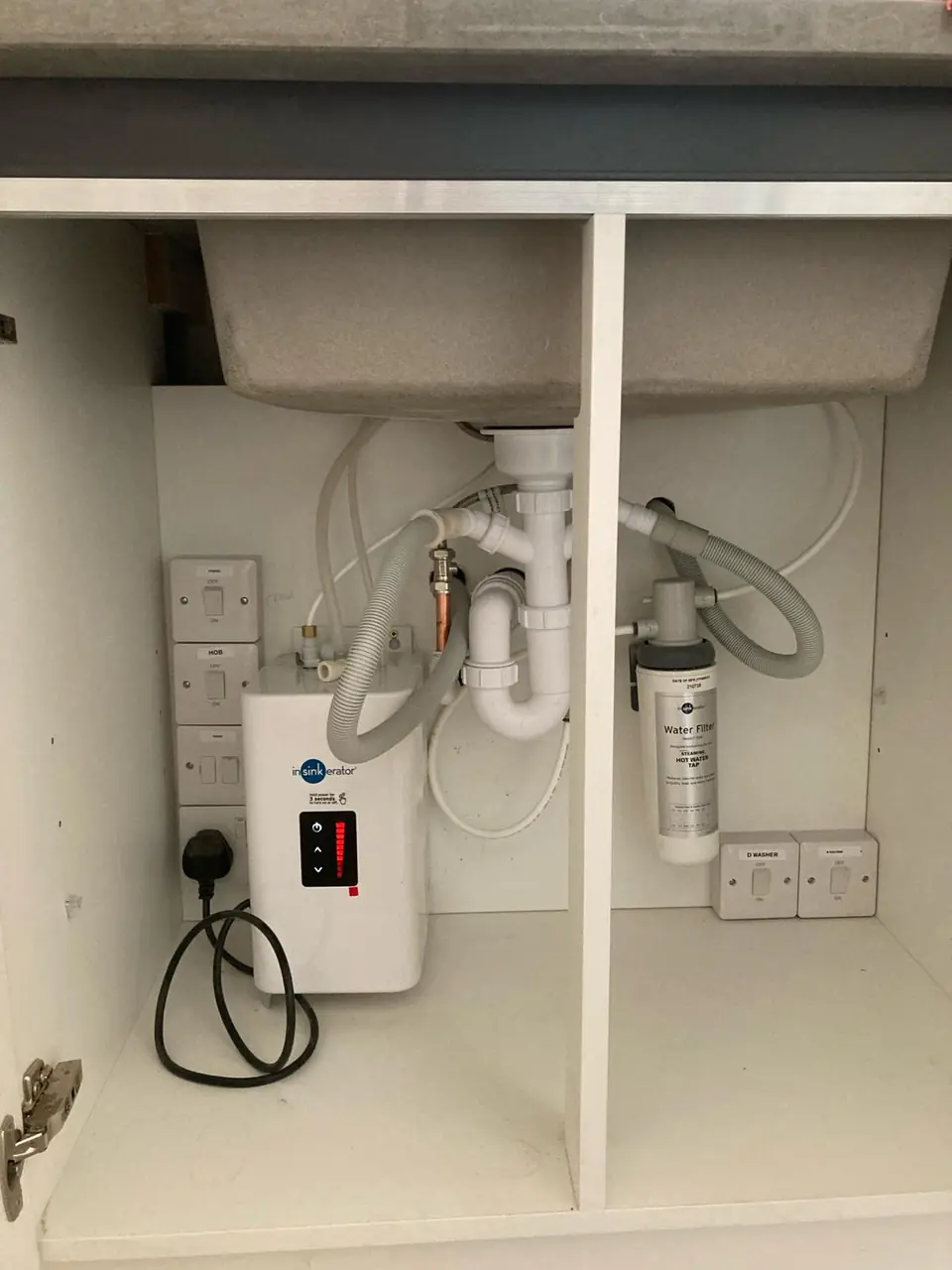 Under-sink electric water heater and filter neatly plumbed in a kitchen cupboard